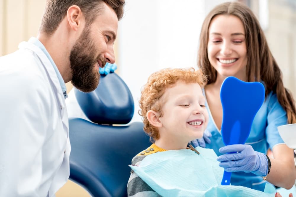 Happy dental team with young patient